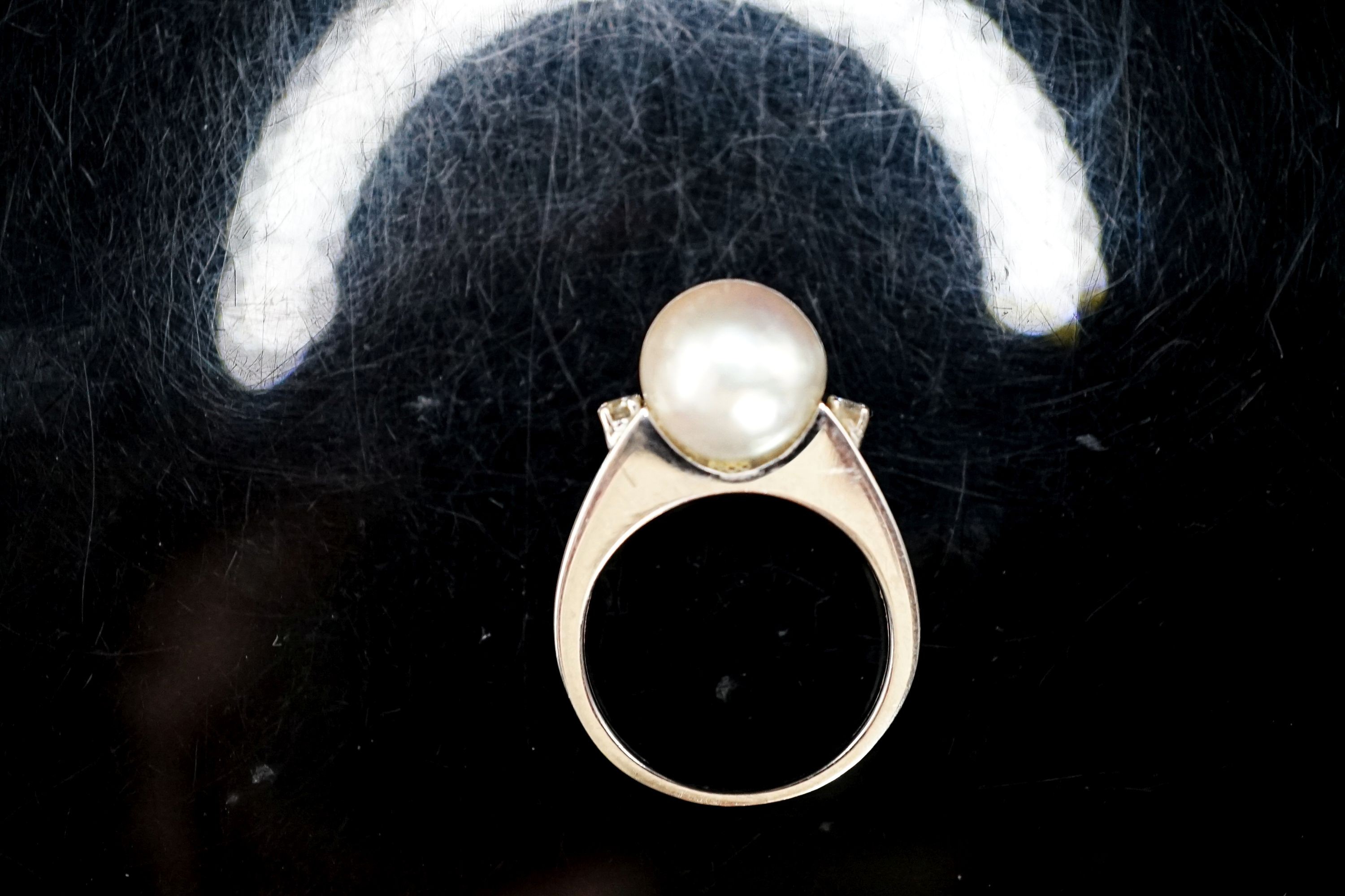 A white metal and single stone cultured pearl dress ring, with diamond set shoulders, size L/M, gross 4.1 grams.